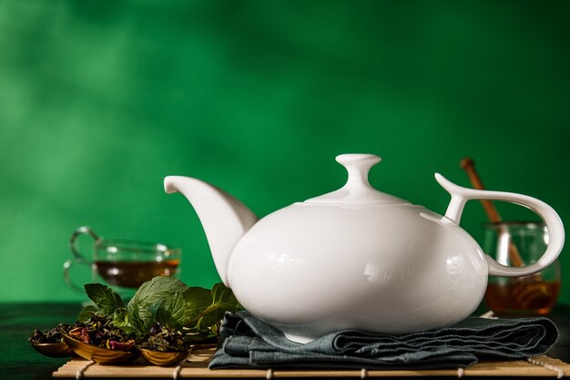 Teapot in arrangement with aromatic herbs