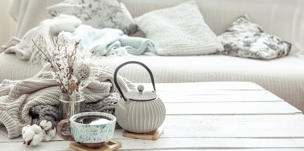 A teapot and a beautiful ceramic cup with decor details in a hygge style living room