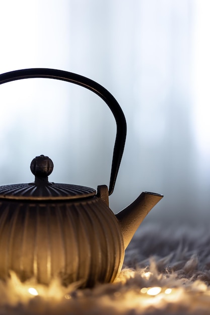 Teapot on a blurred background in the dark with garlands