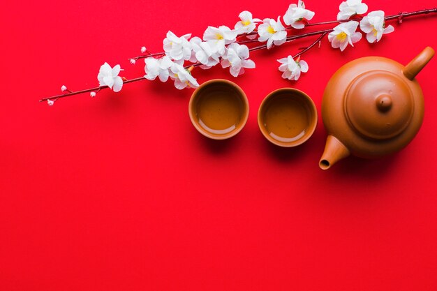 Teapot and cups near cherry branch