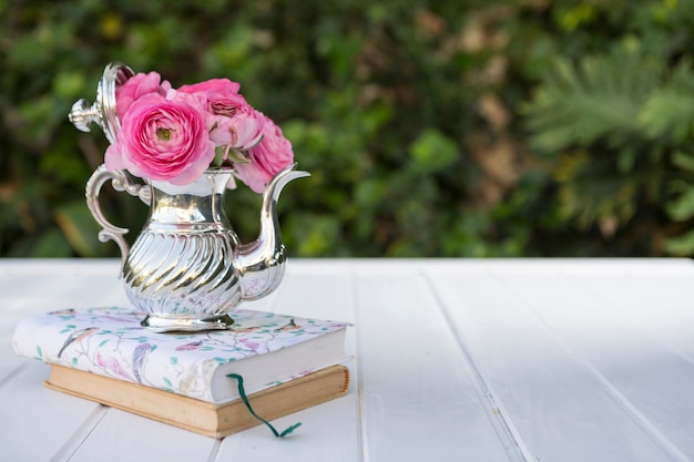 Free photo teapot with flowers on some books