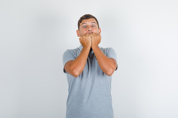 Free photo technical service man biting his fists in grey t-shirt and looking nervous