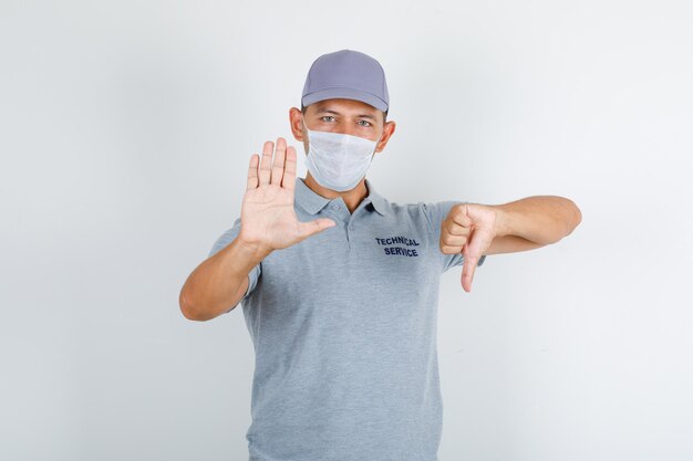 Technical service man doing stop sign with thumb down in grey t-shirt with cap