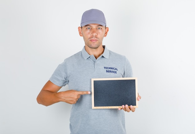 Technical service man in grey t-shirt with cap holding blackboard