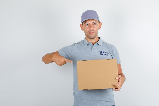 Technical service man pointing finger at cardboard box in grey t-shirt with cap