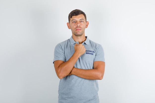 Technical service man standing with clenched fist in grey t-shirt and looking serious