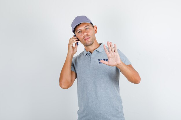 기술 서비스 남자 모자와 회색 티셔츠에 제스처없이 전화 통화