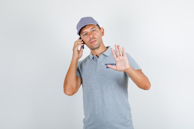 Technical service man talking on phone with no gesture in grey t-shirt with cap