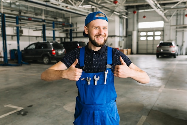 Technician in coveralls with wrenches at workshop