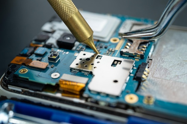 Technician repairing inside of mobile phone by soldering iron. integrated circuit. the concept of data, hardware, technology.
