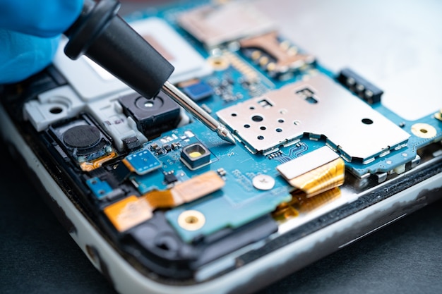 Technician repairing inside of mobile phone by soldering iron