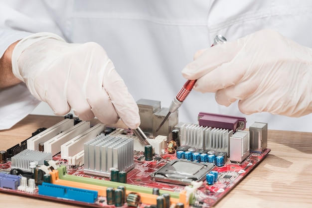 Technician wearing gloves working on computer motherboard