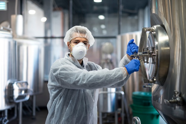 Foto gratuita tecnologo lavoratore industriale apertura serbatoio di lavorazione nella linea di produzione in fabbrica