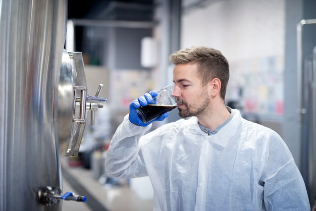 Technologist tasting beer quality at modern brewery