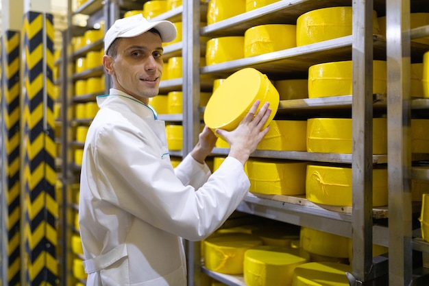 チーズを手にした技術者が、乳製品工場の部門で生産準備の整った検査を行います