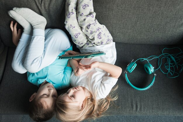 Концепция технологии с детьми, лежащими на диване