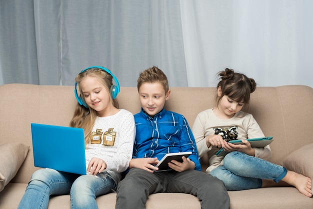 Концепция технологии с тремя детьми на диване