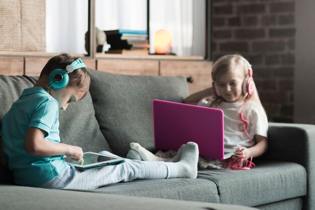 Концепция технологии с двумя детьми на диване
