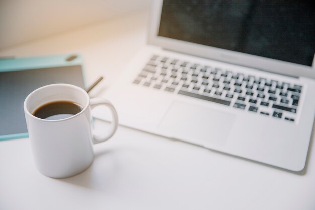 Technology and desk concept with coffee and laptop