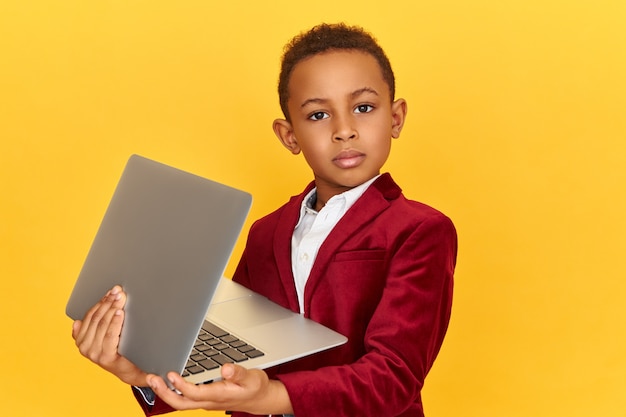 기술, 전자 기기 및 장치 개념. 무선 고속 인터넷 연결을 사용하여 자신의 손에 노트북과 격리 포즈 자신감 어두운 피부 어린 소년의 스튜디오 이미지