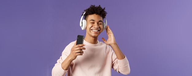 Technology and lifestyle concept portrait of carefree attractive young man enjoying fine sound liste