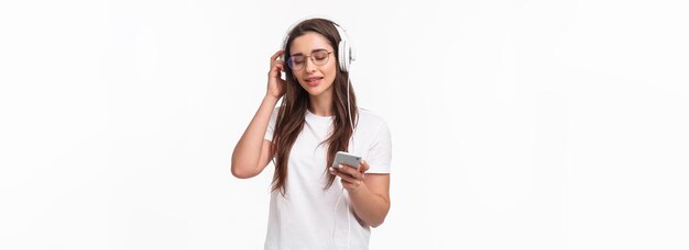 Technology lifestyle and music concept portrait of pleased and relaxed young woman vibing and chilli