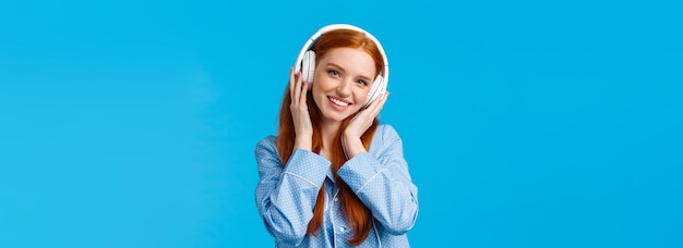 Free photo technology lifestyle and people concept cute redhead woman in pyjama listen music in headphones enjo