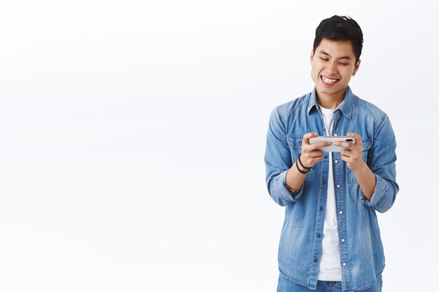 Technology, online lifestyle concept. Portrait of excited smiling guy compete with friend online game, trying to win or beat score