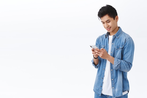 Technology, online lifestyle concept. Portrait of handsome young taiwanese man sending message