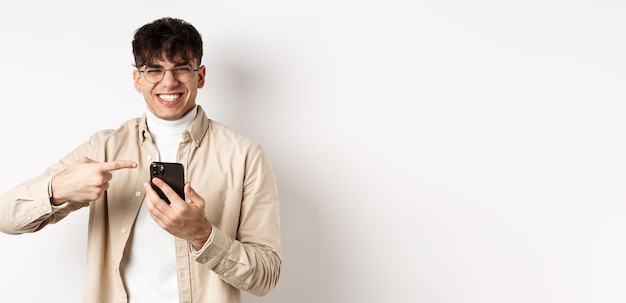 Technology and online shopping concept portrait of natural man in glasses laughing and pointing fing