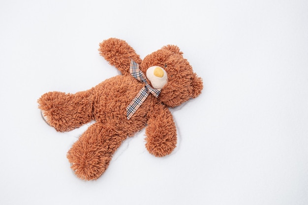 A teddy bear lies alone among the snow