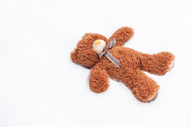 A teddy bear lies alone among the snow