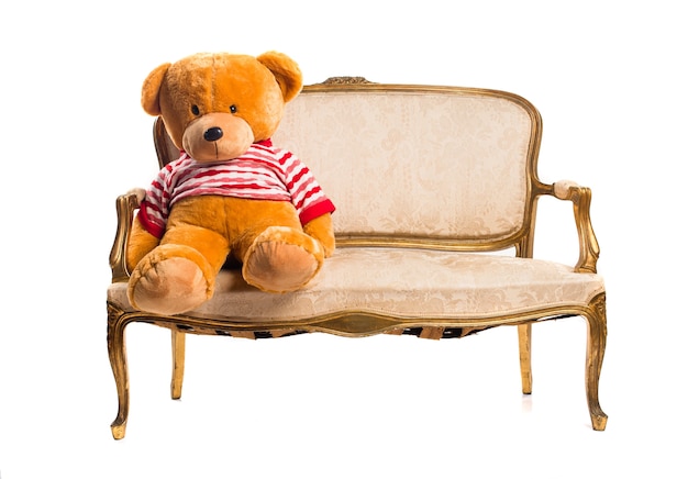 Бесплатное фото Тедди, сидящий на старинном кресле