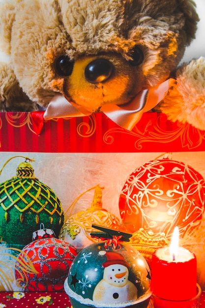 Бесплатное фото teddybear в сумке с декоративными рождественскими украшениями и освещенной свечой