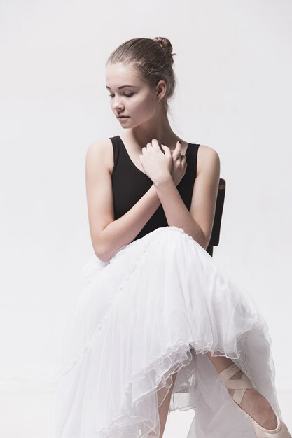The teen ballerina in white pack sitting on chair