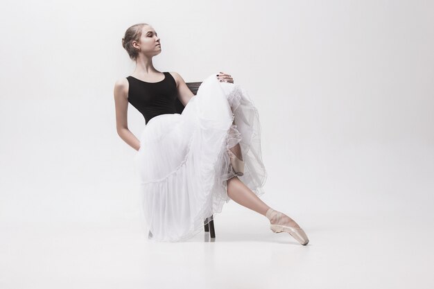 Молодая балерина в белом пакете сидит на стуле