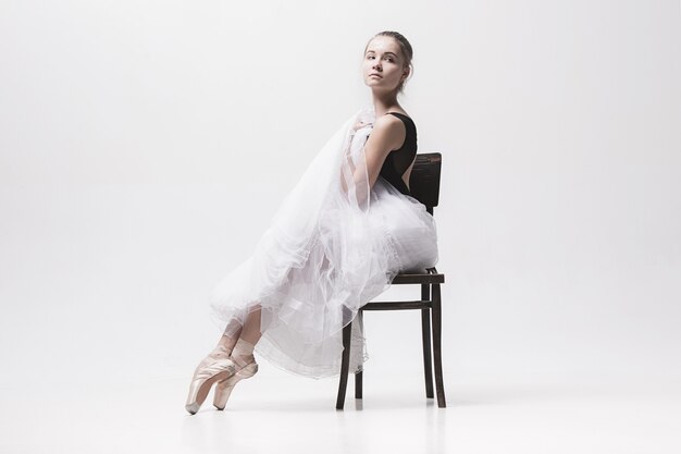 The teen ballerina in white pack sitting on chair