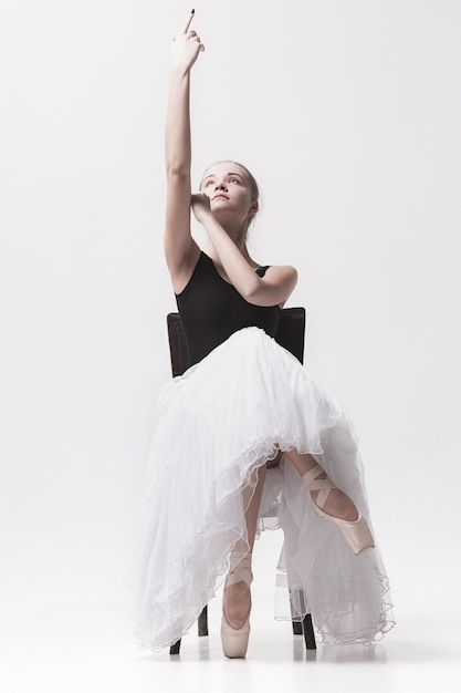 Teen ballerina in white skirt posing on the chair