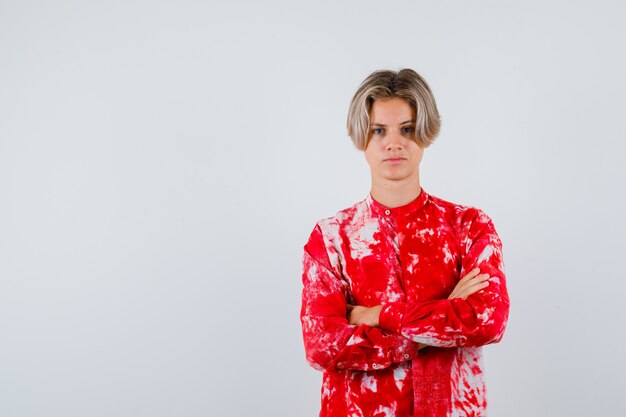 Free photo teen blonde male in oversize shirt holding arms folded and looking pensive , front view.