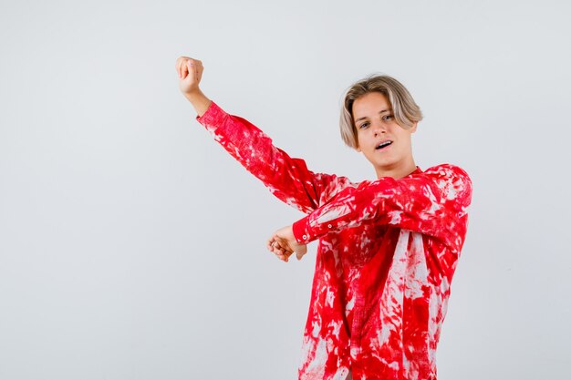 Teen blonde male in oversized shirt stretching upper body and looking fatigued