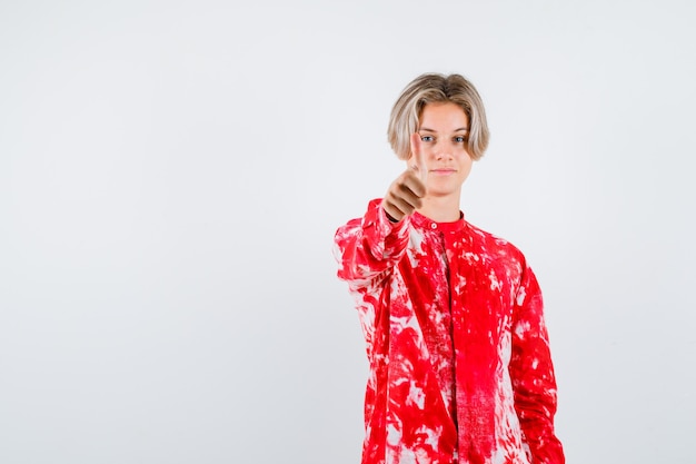 Teen blonde male showing thumb up in oversize shirt and looking confident. front view.