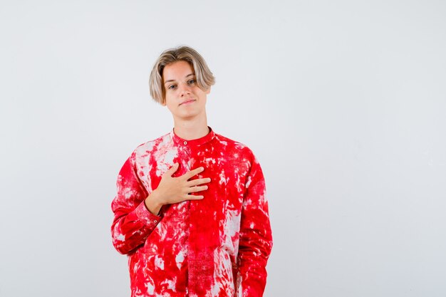 Teen blonde male with hand on chest in oversized shirt and looking merry. front view.