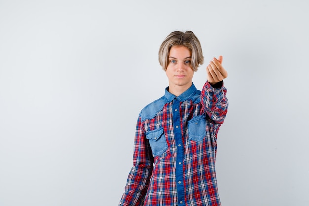 Teen boy in checkered shirt showing money gesture and looking confident , front view.