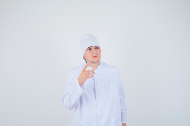 teen boy in doctor uniform pointing up and looking thoughtful