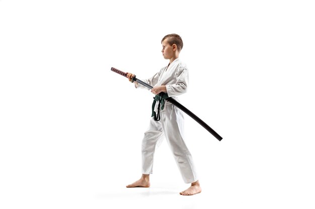 Free photo teen boy fighting at aikido training in martial arts school. healthy lifestyle and sports concept. fightrer in white kimono on white wall. karate man with concentrated face in uniform.