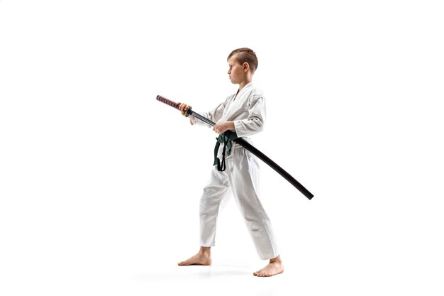Teen boy fighting at Aikido training in martial arts school. Healthy lifestyle and sports concept. Fightrer in white kimono on white wall. Karate man with concentrated face in uniform.