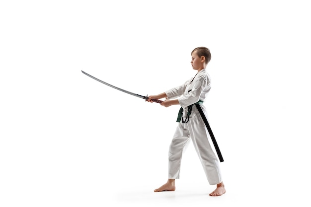 Мальчик-подросток борется на тренировках по айкидо в школе боевых искусств. Концепция здорового образа жизни и спорта. Боец в белом кимоно на белой стене. Человек каратэ с сосредоточенным лицом в униформе.