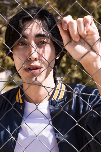 Free photo teen boy gripping fence in street