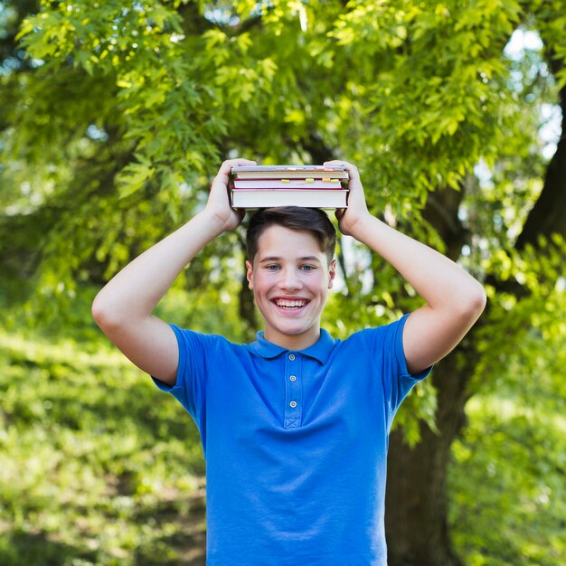 Teen boy holding books on his head