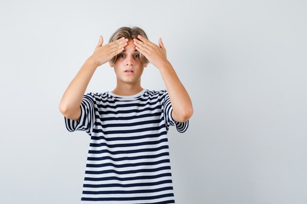 Teen boy keeping hands on forehead in t-shirt and looking worried , front view.